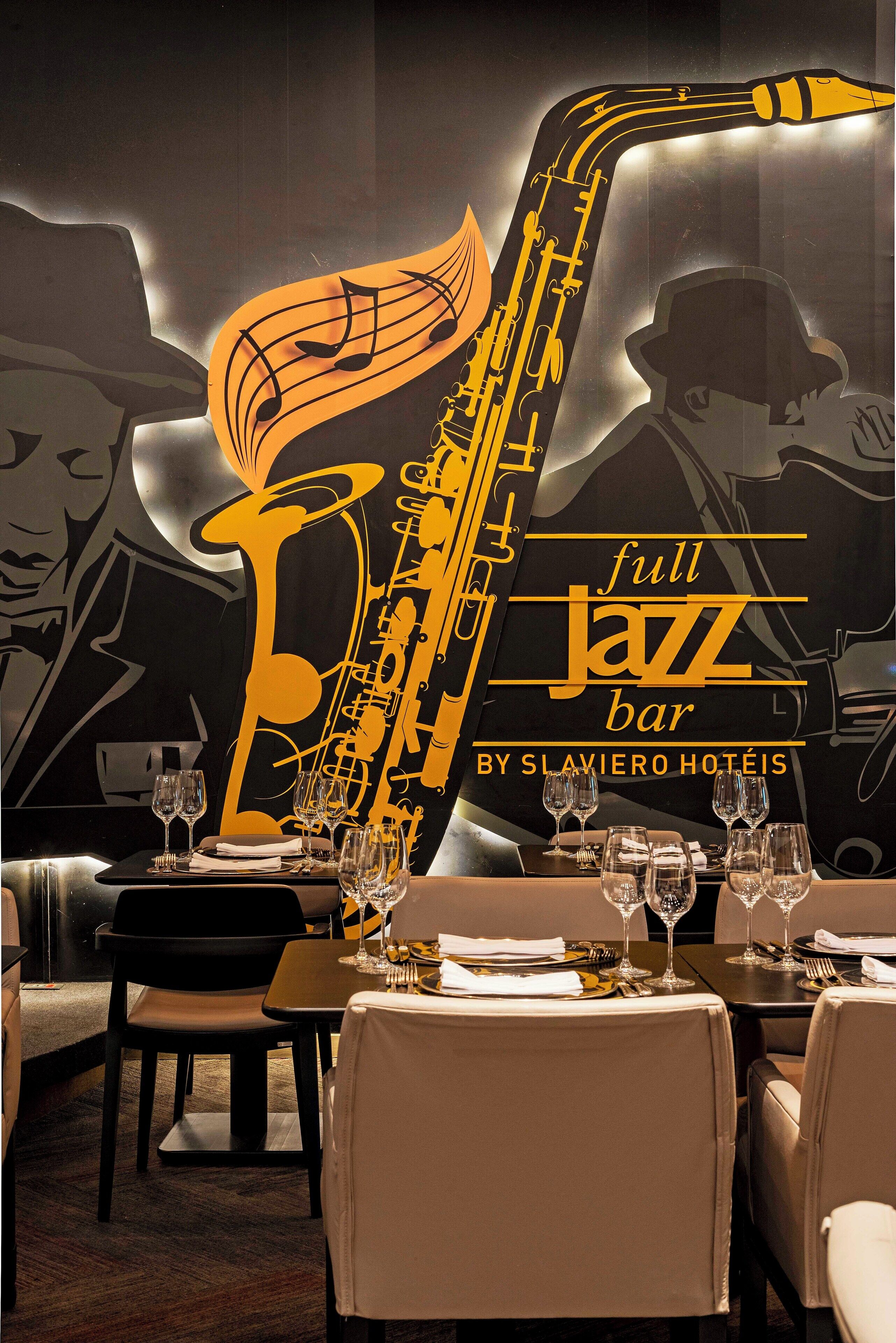 A restaurant interior with tables set for dining, a saxophone graphic, and the text "full jazz bar by Slaviero Hotéis".