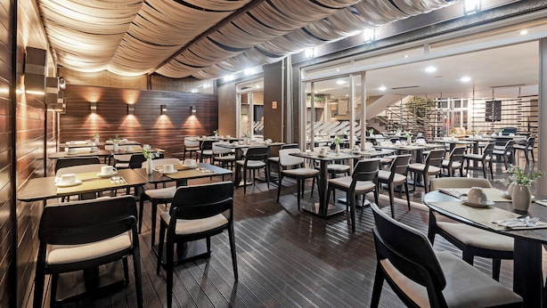 Un restaurante con paredes de paneles de madera, mesas con sillas y un techo con diseño drapeado.