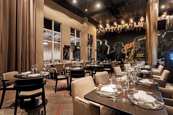 A restaurant with multiple tables set for dining, featuring a jazz-themed mural on the wall.