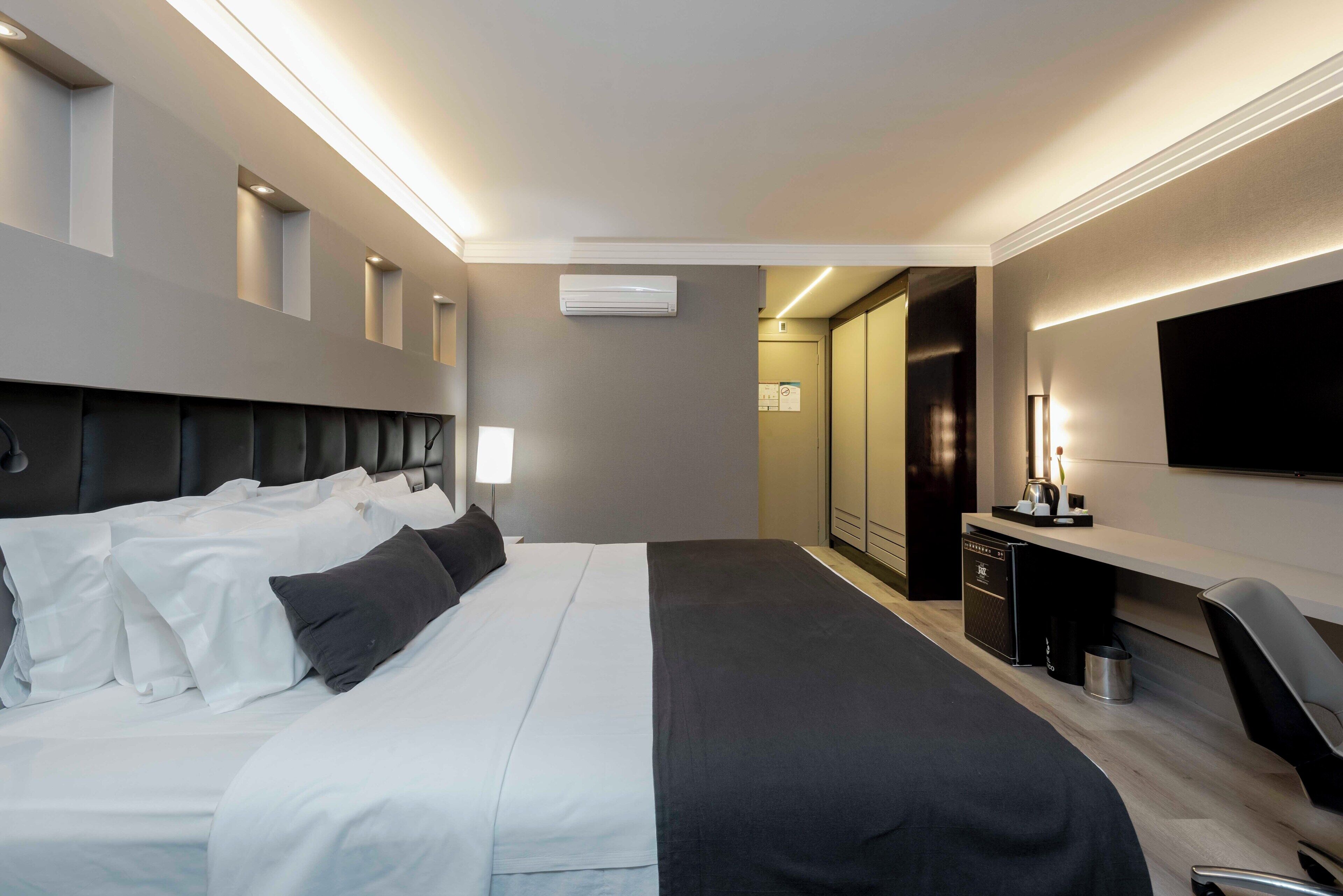 Une chambre d’hôtel moderne, dotée d’un grand lit, d’une table de chevet et d’un bureau avec une chaise.
