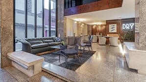 A modern lobby with a leather sofa, clear chairs, a coffee table, and a bar area with a sign reading "DRY BAR". - SLAVIERO Curitiba Centro  (Curitiba)