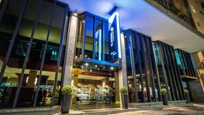 A modern hotel with a prominent sign, large windows, and a well-lit entrance. - SLAVIERO Curitiba Centro  (Curitiba)
