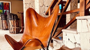 Un interior moderno con una pared de piedra, una escalera de madera y un sillón de cuero marrón.