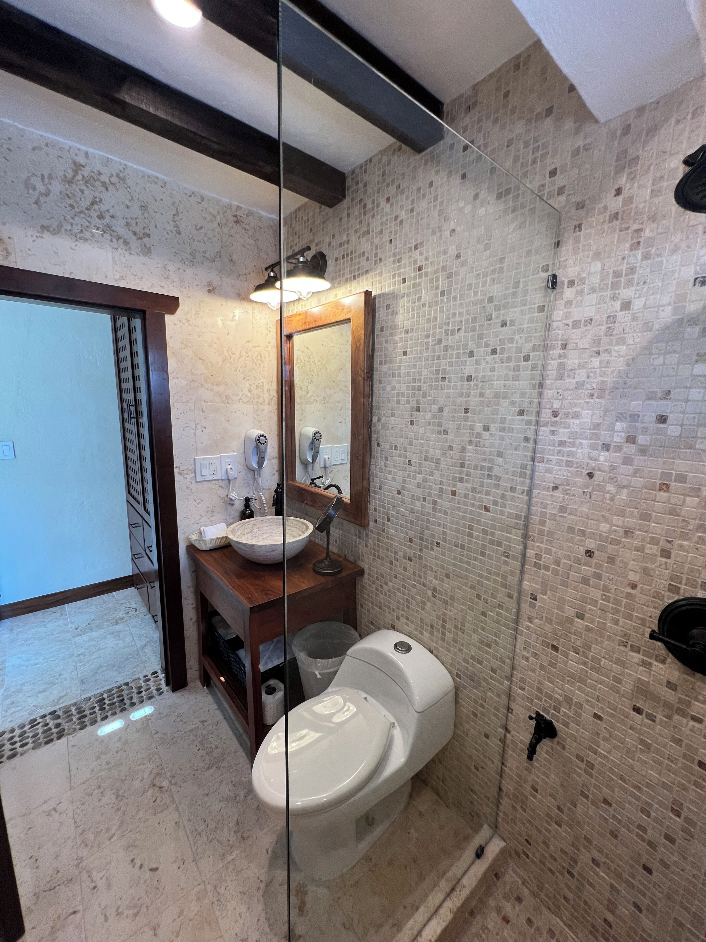 A bathroom with a glass shower enclosure, a sink with a mirror, and a toilet.