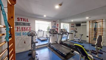 Un gimnasio con cintas de correr, elípticas y máquinas de pesas.