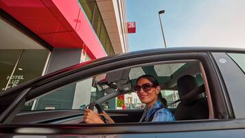 A car interior with a driver wearing sunglasses and a striped shirt.