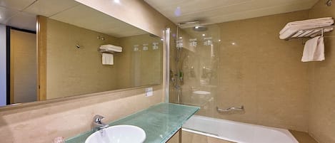 A modern bathroom with a glass sink, a large mirror, a glass-enclosed shower, and a white bathtub.