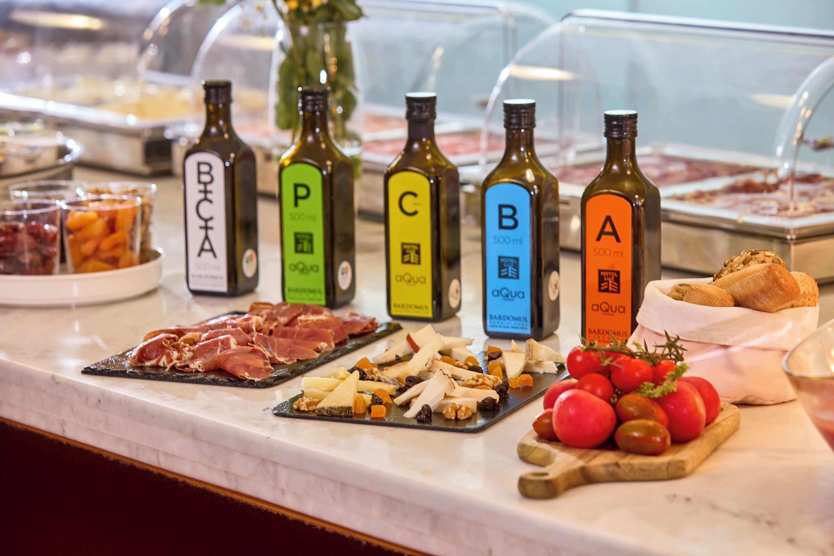 Um balcão de buffet com diversos alimentos e garrafas de azeite identificadas com letras.