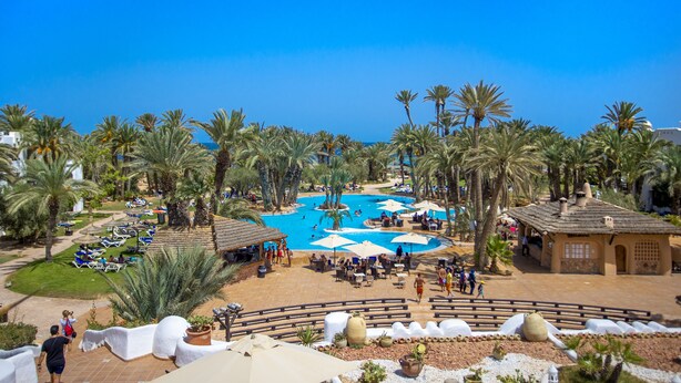 A resort with a central pool area surrounded by palm trees and lounge chairs. -  Odyssee Resort and Thalasso (Zarzis)