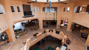 A spacious lobby with a central courtyard, multiple seating areas, and a grand chandelier. -  Odyssee Resort and Thalasso (Zarzis)