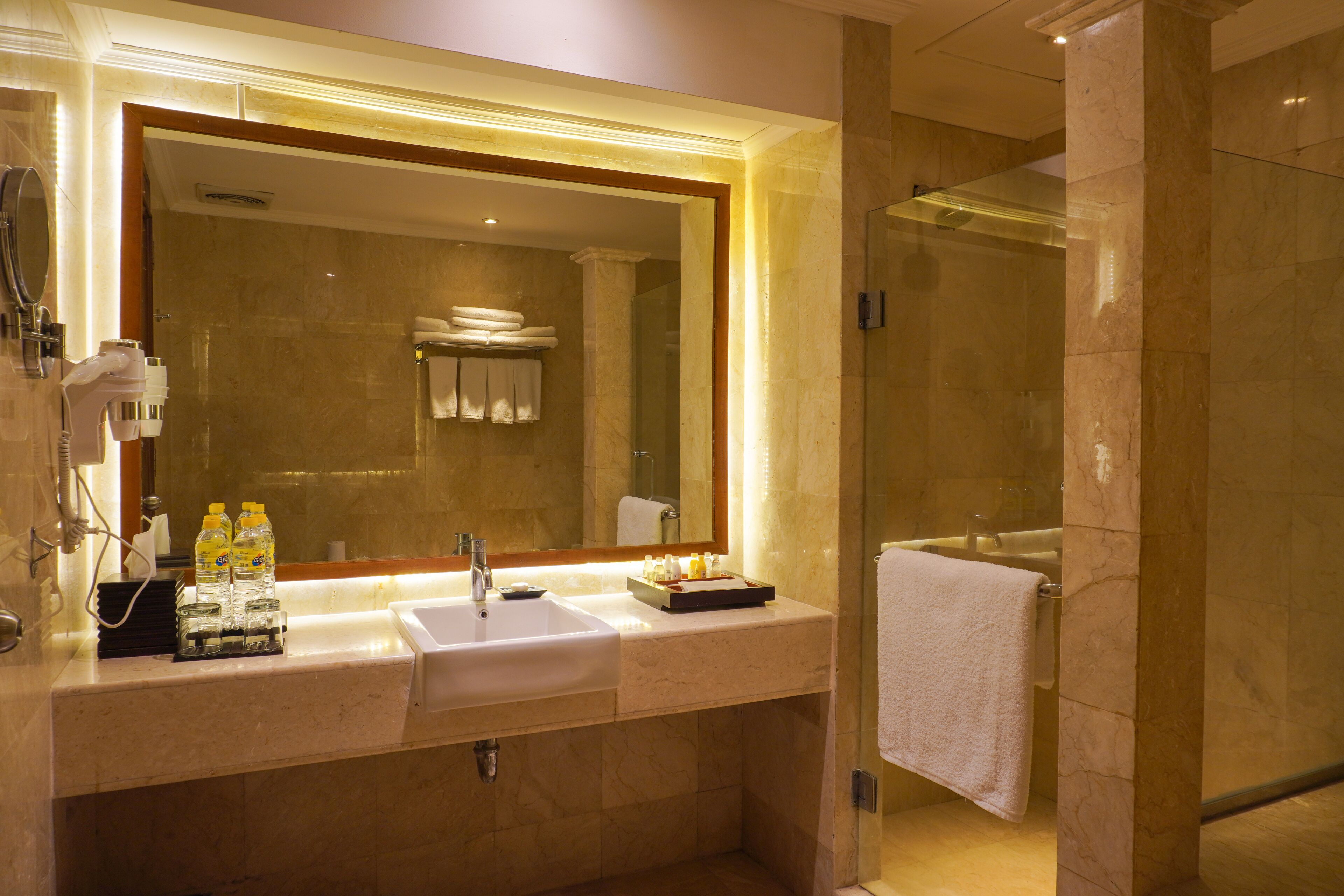Un baño moderno con un espejo grande, dos lavamanos y una cabina de ducha de vidrio.