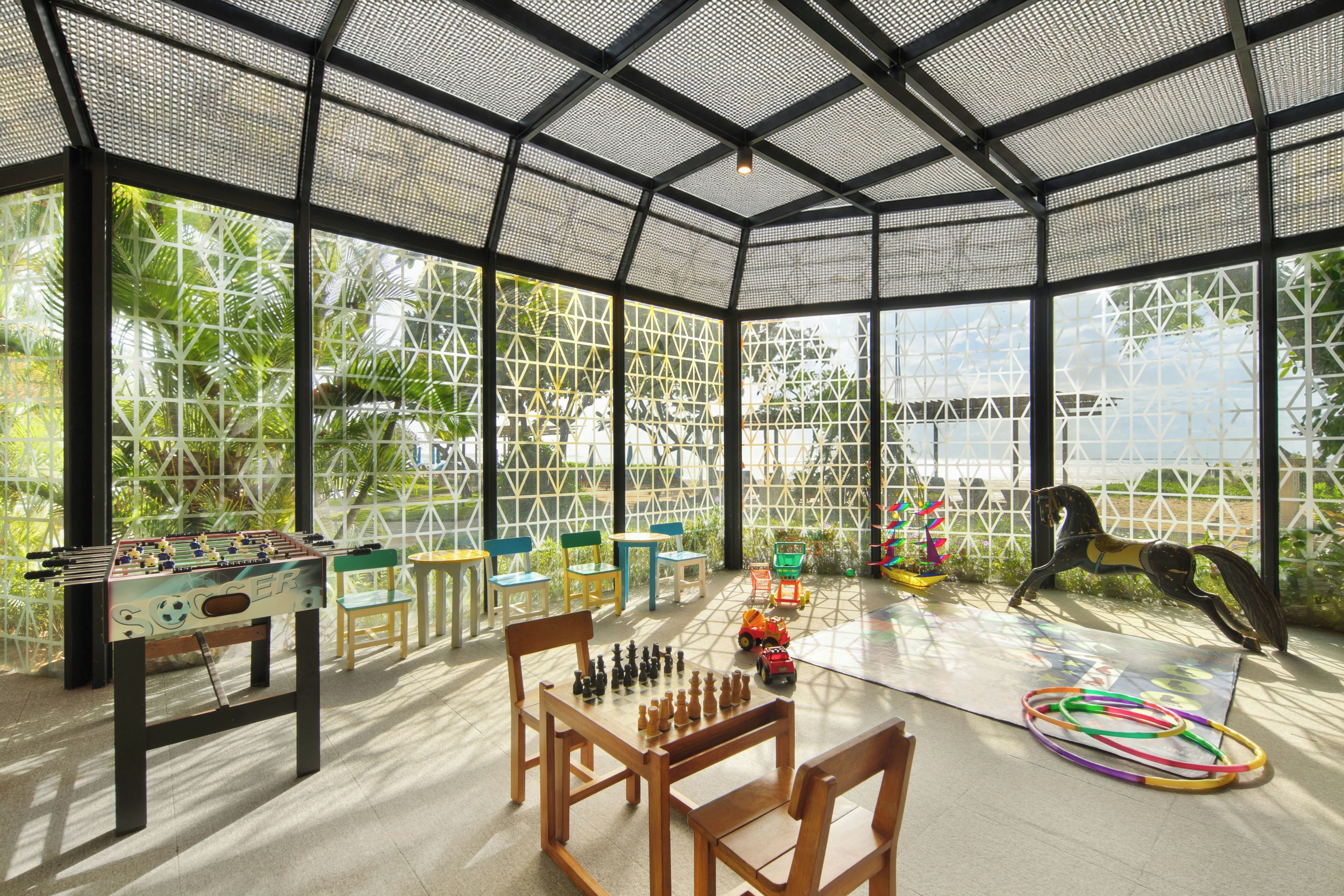 An indoor recreational area with a foosball table, chess table, and a colorful play area.