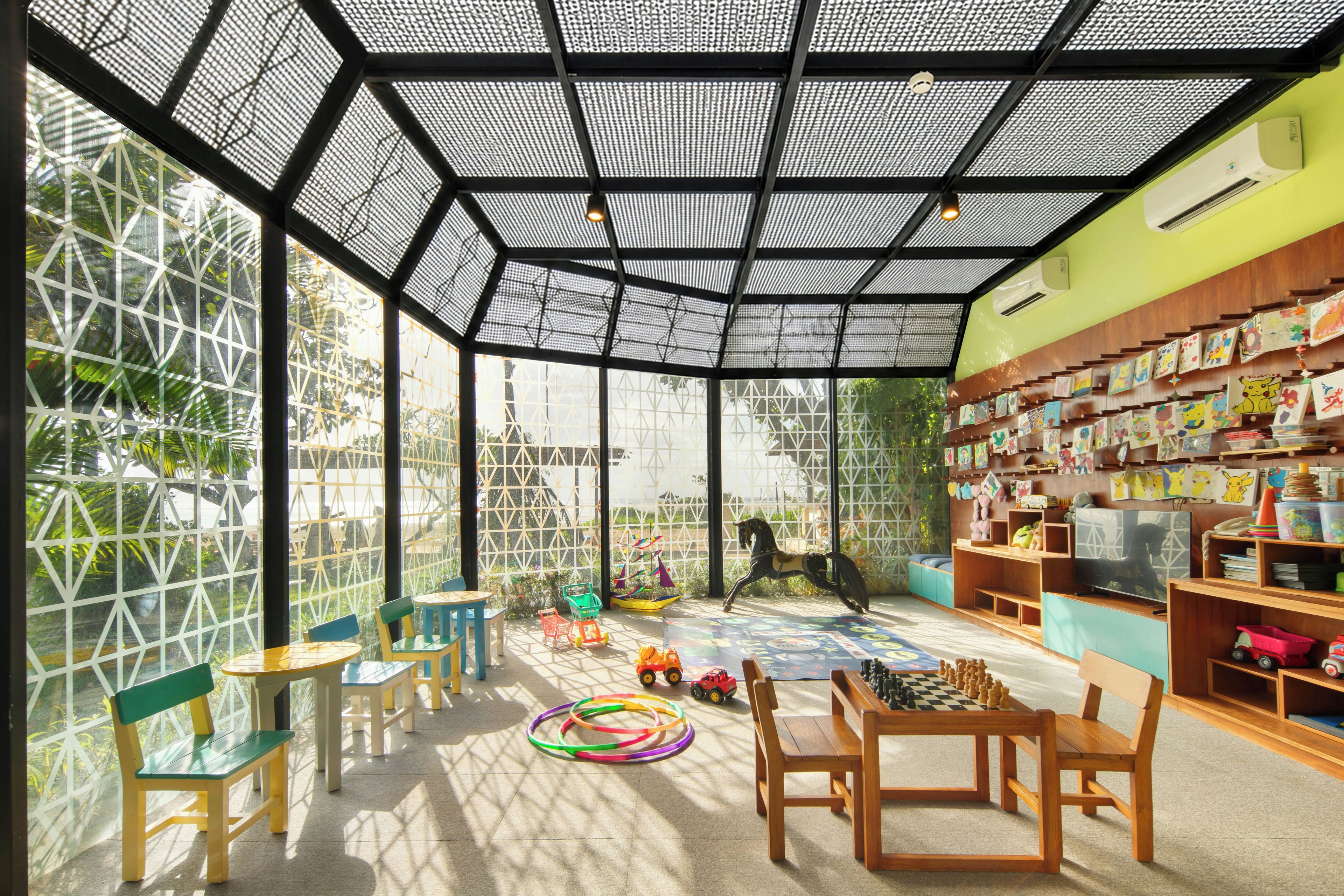 A spacious indoor area with a high ceiling, geometric patterned walls, and a variety of children's toys and activities.