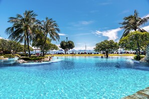 Una piscina azul cristalina rodeada de palmeras y sillas de descanso, bajo un cielo despejado.