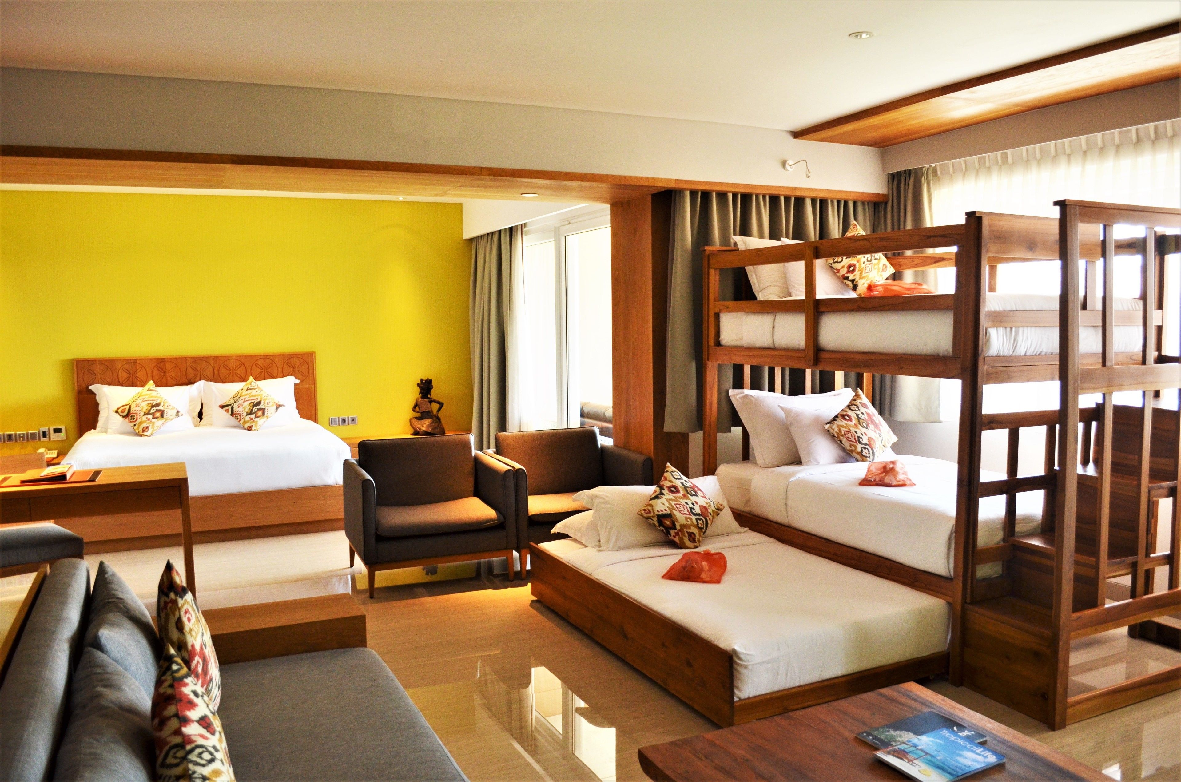 A hotel room with two beds, a sofa, a coffee table, and a chair.