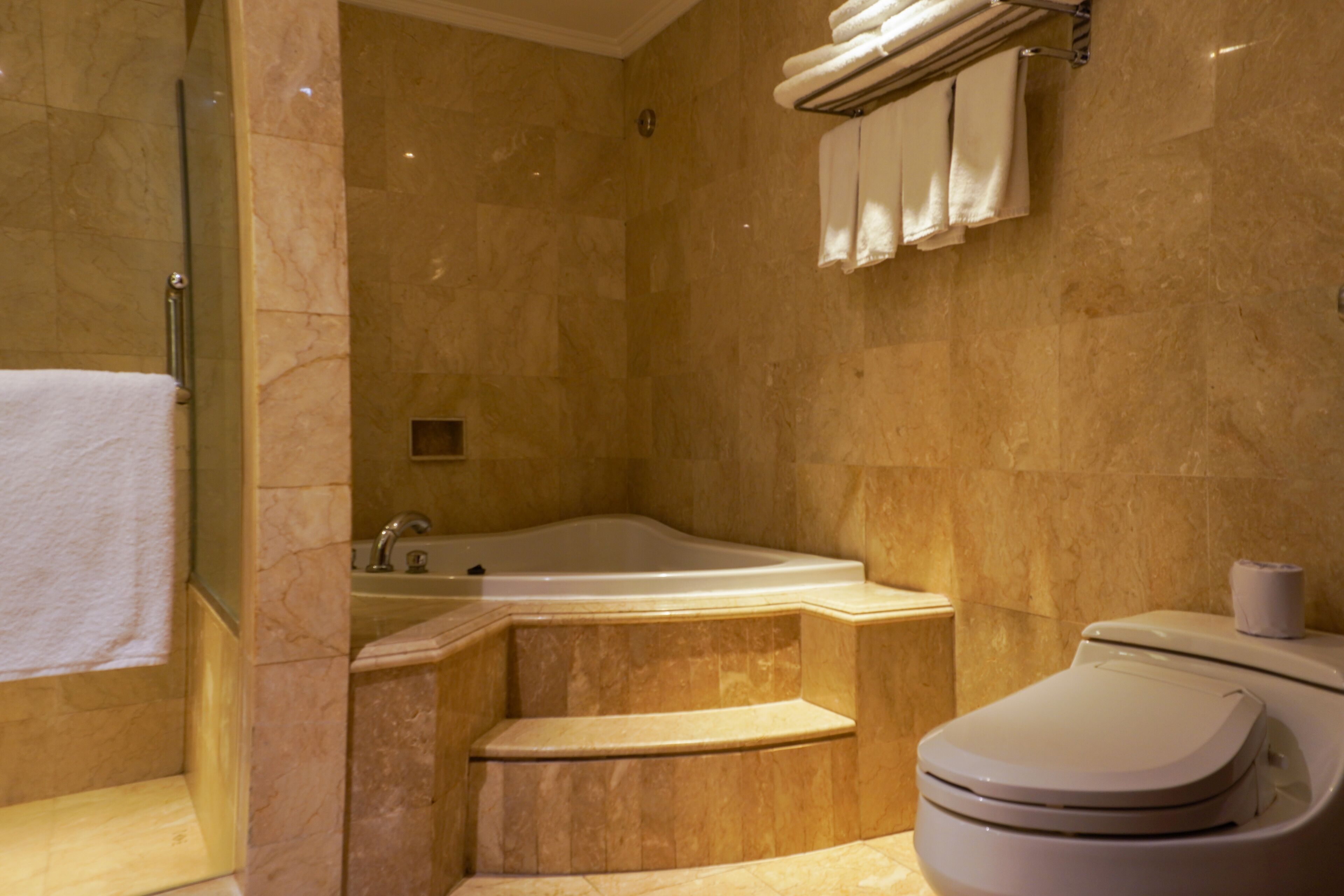 A bathroom with a bathtub, toilet, and a glass shower enclosure.