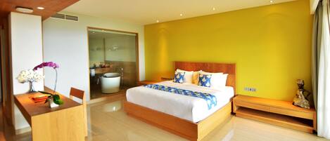 A modern hotel room with a large bed, a wooden desk, and a bathroom visible through an open door.