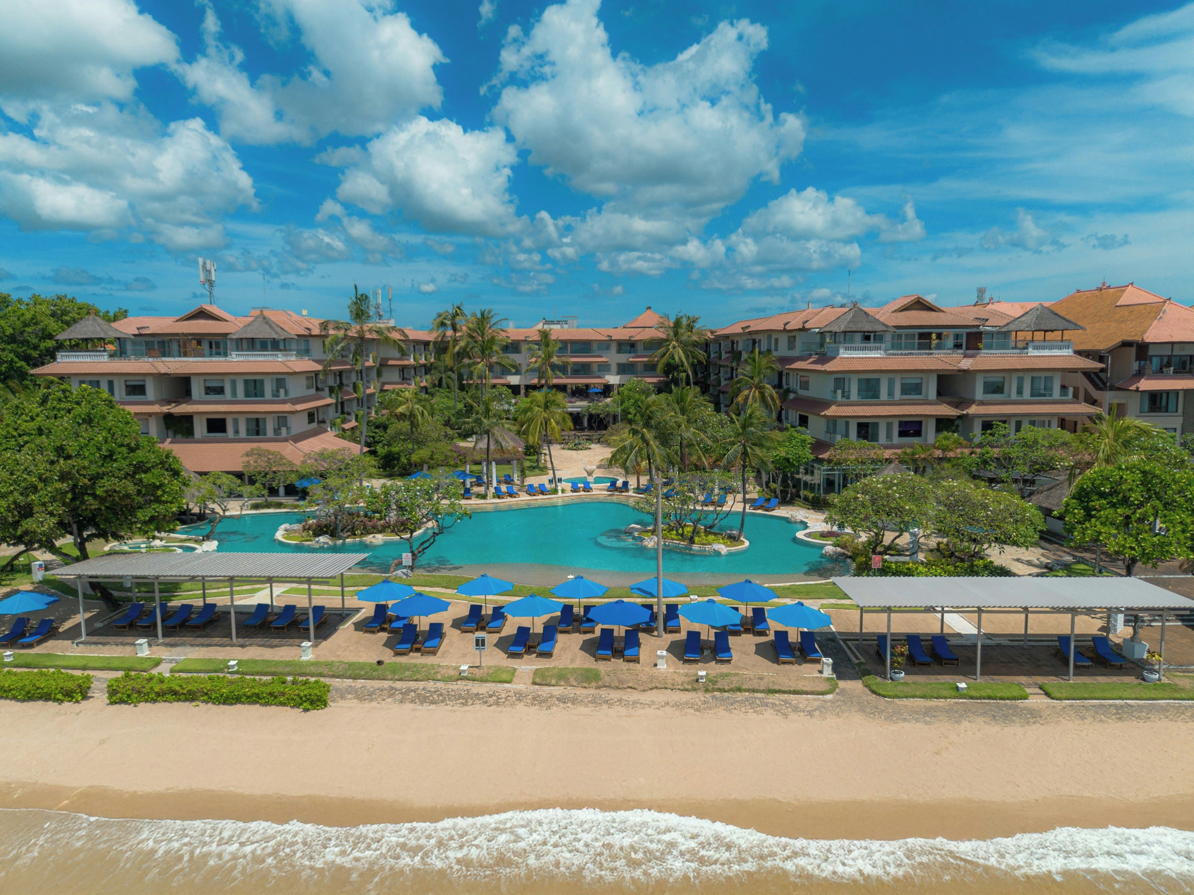 A resort with a swimming pool, beach, and multiple-story buildings.