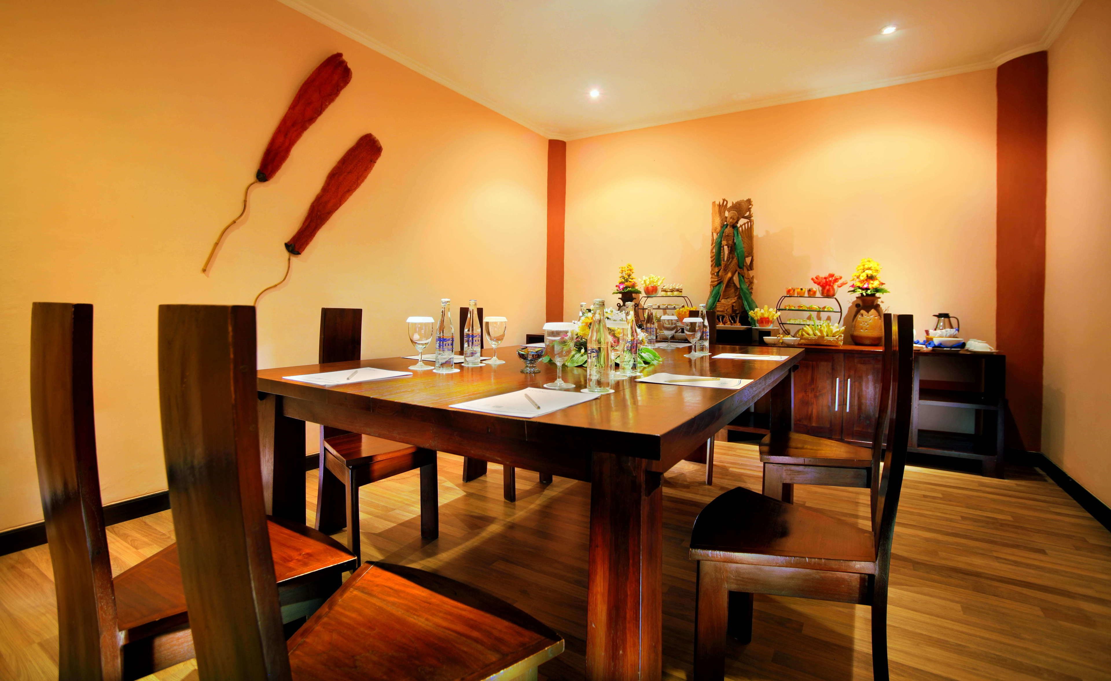 A dining area with a wooden table set for a meal, chairs, and a decorative wall piece.