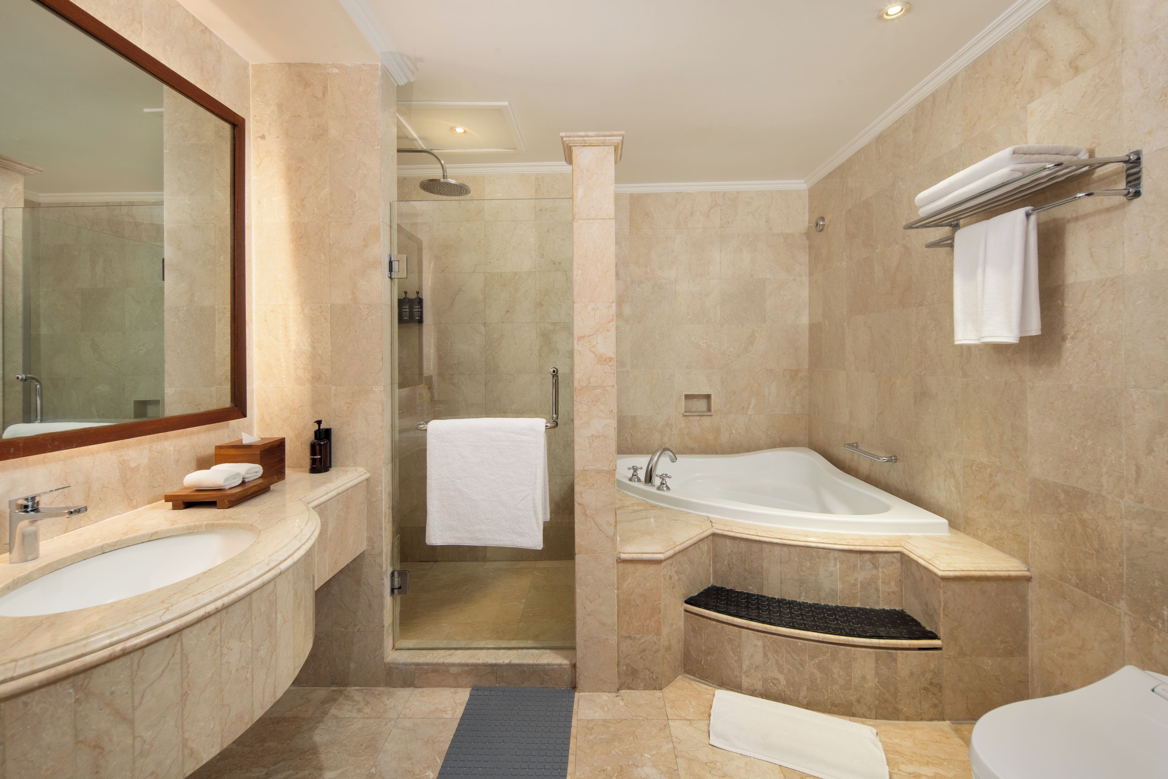 A modern bathroom with a large mirror, two sinks, a bathtub, and a shower area.