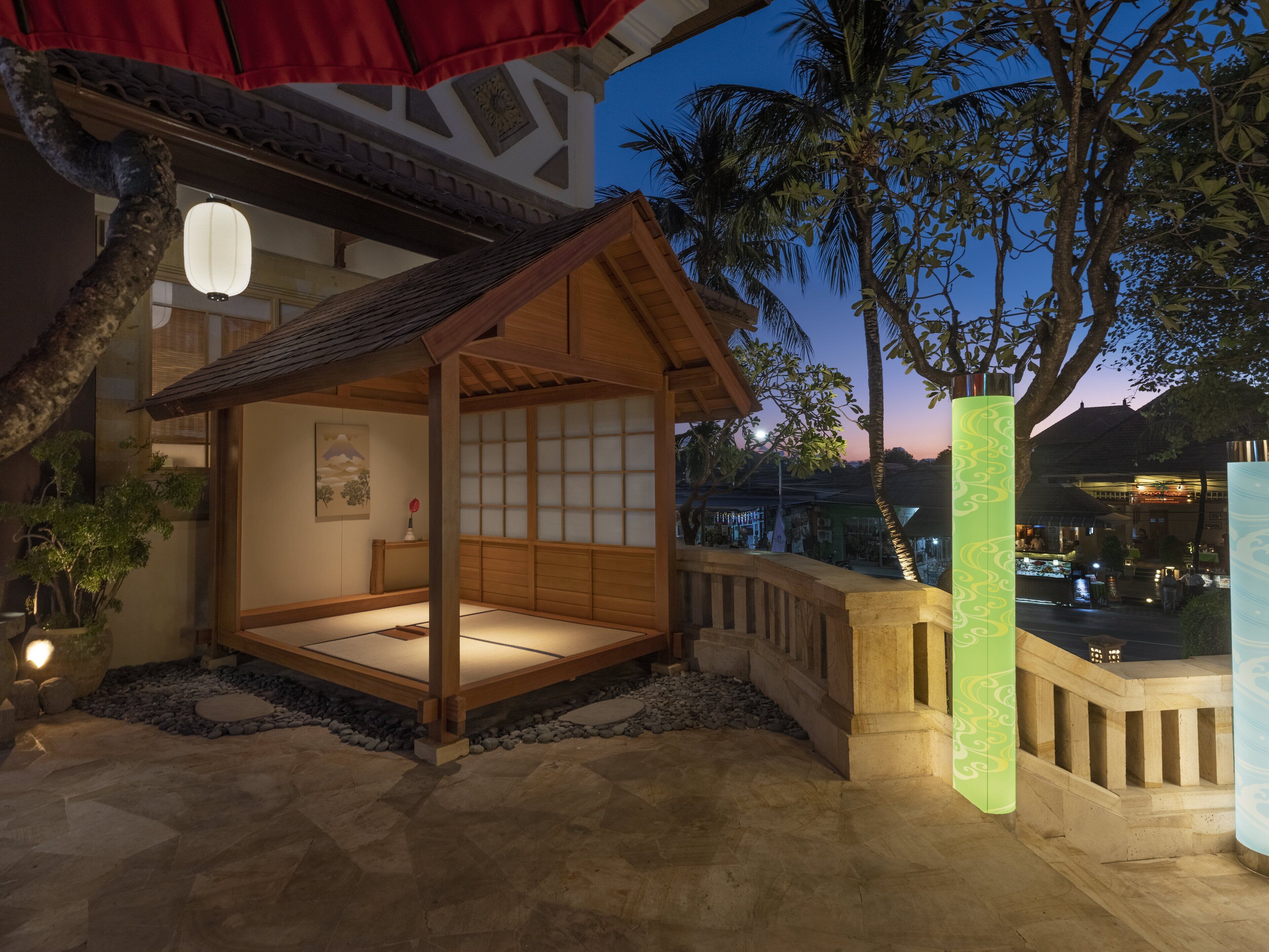 A traditional Japanese-style room with tatami flooring, a shoji screen wall, and a wooden ceiling.