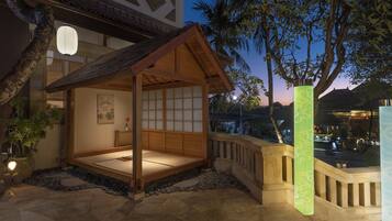 A traditional Japanese-style room with tatami flooring, a shoji screen wall, and a wooden ceiling.
