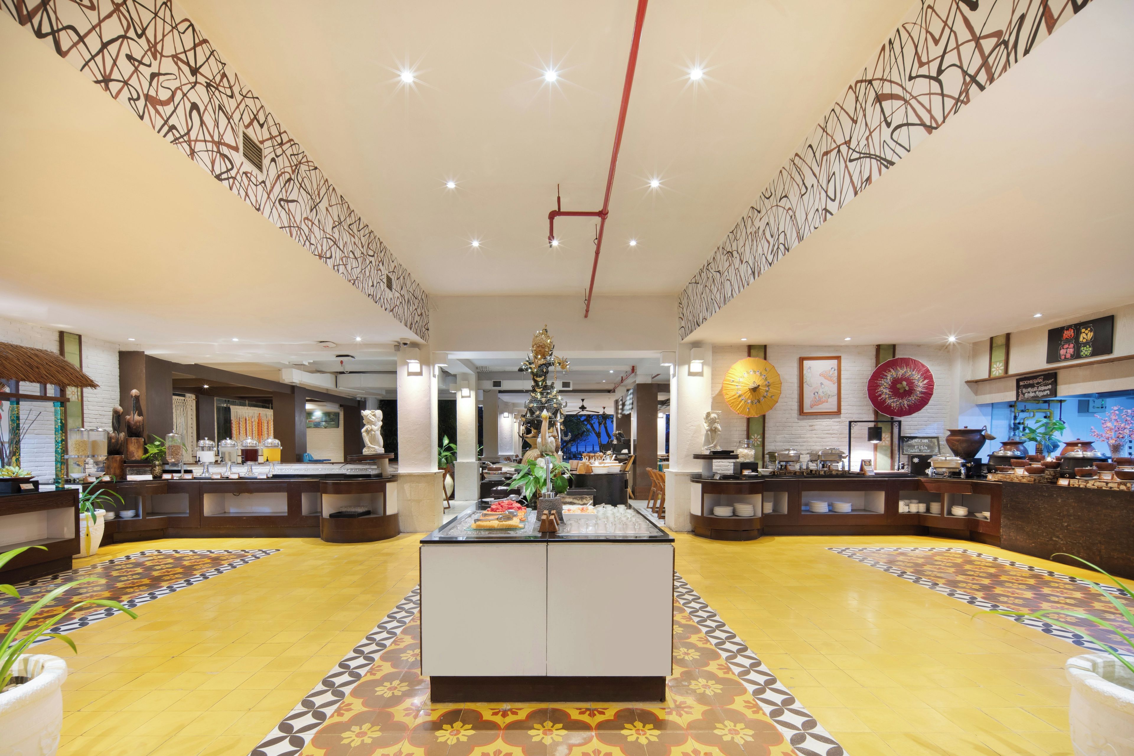 A spacious lobby with a central island, decorative wall patterns, and a variety of amenities including a buffet area.