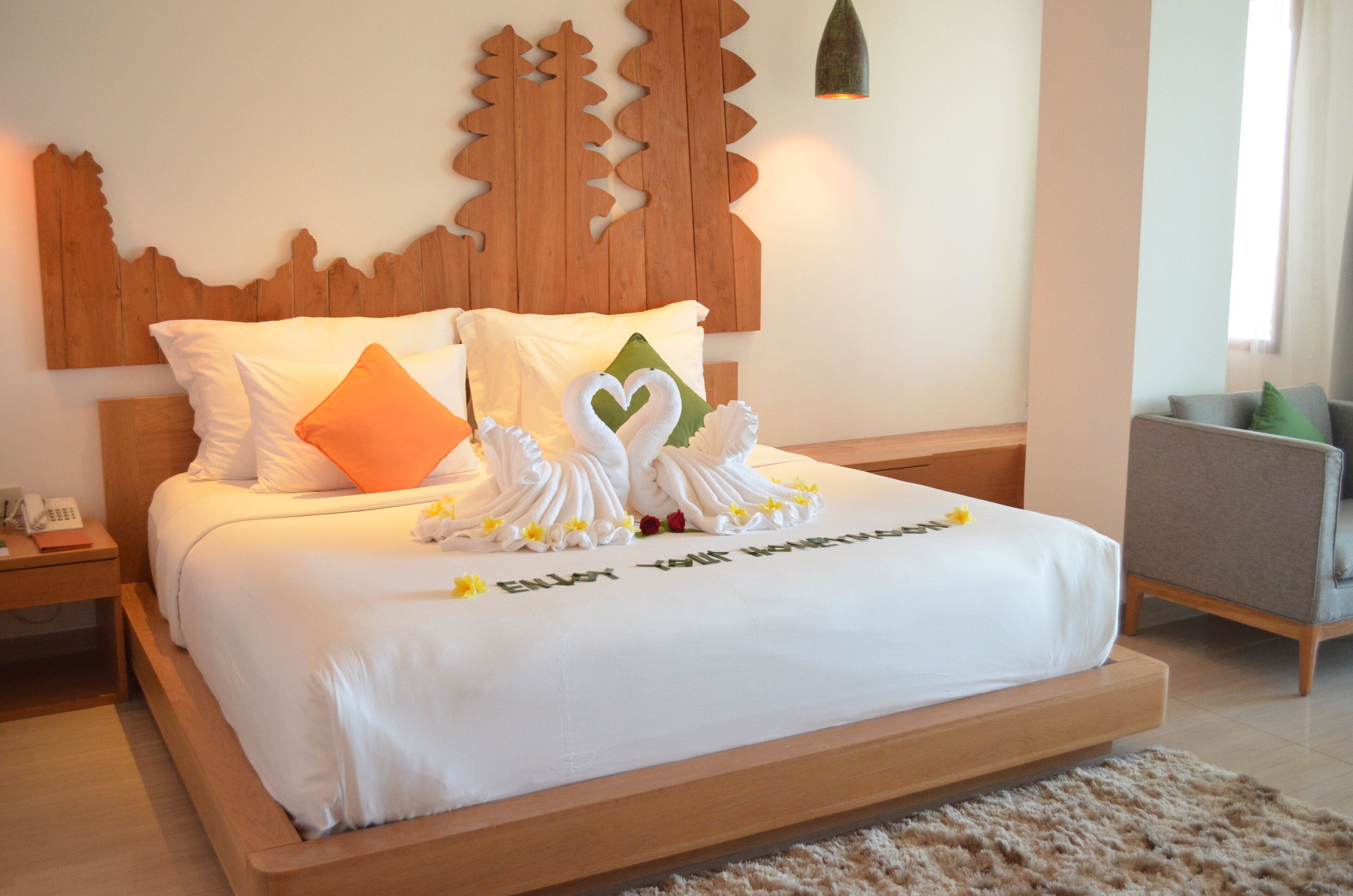 A neatly made bed with white linens, two pillows, and a decorative swan towel arrangement.