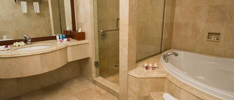 A bathroom with a large bathtub, a glass-enclosed shower, and a vanity with a mirror.