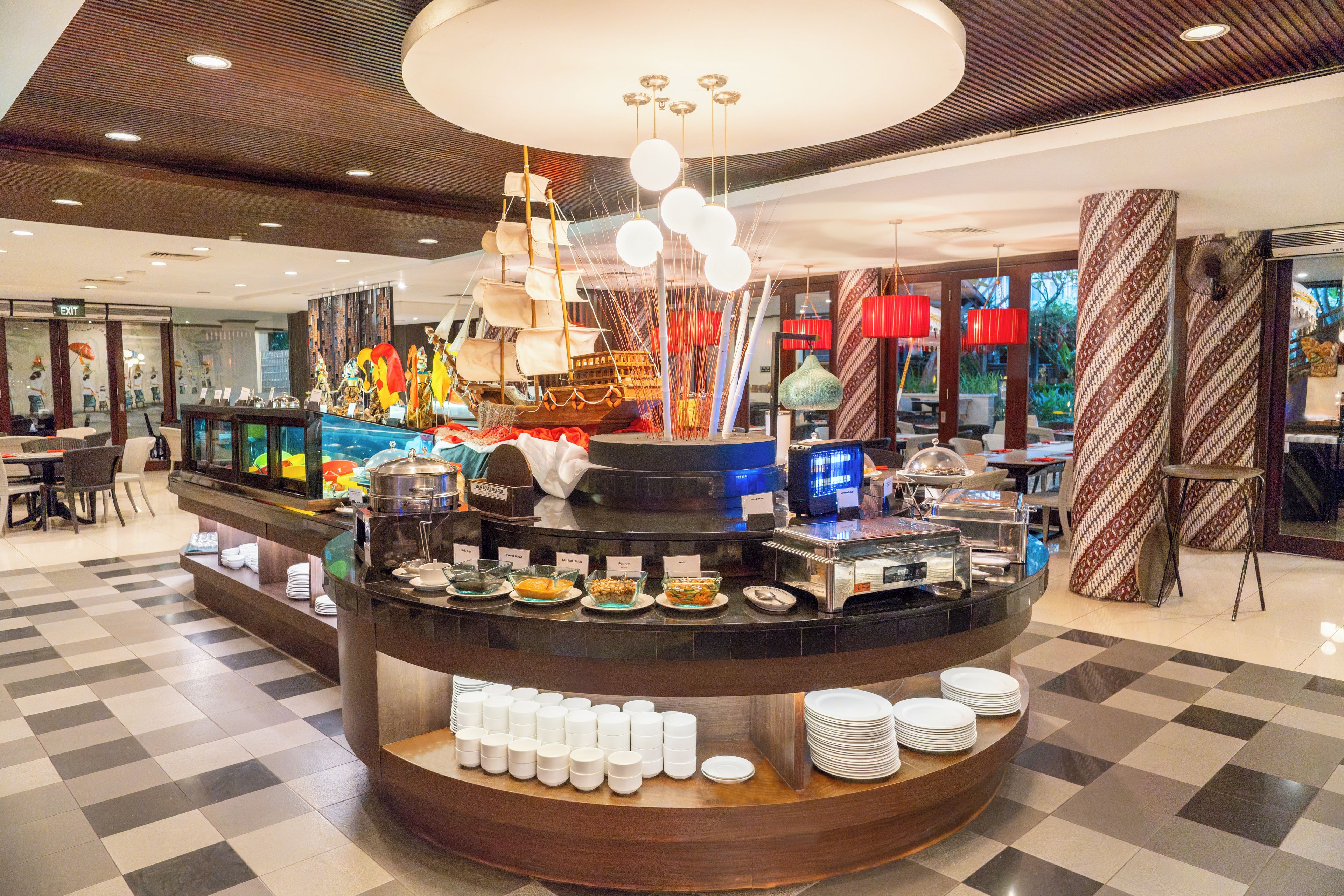 Un área de buffet con diferentes estaciones de comida, una decoración náutica y un suelo a cuadros.