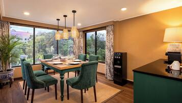 A dining area with a wooden table, green upholstered chairs, and hanging pendant lights.