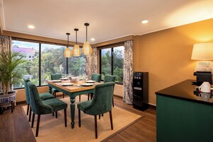 A dining area with a wooden table, green upholstered chairs, and hanging pendant lights.