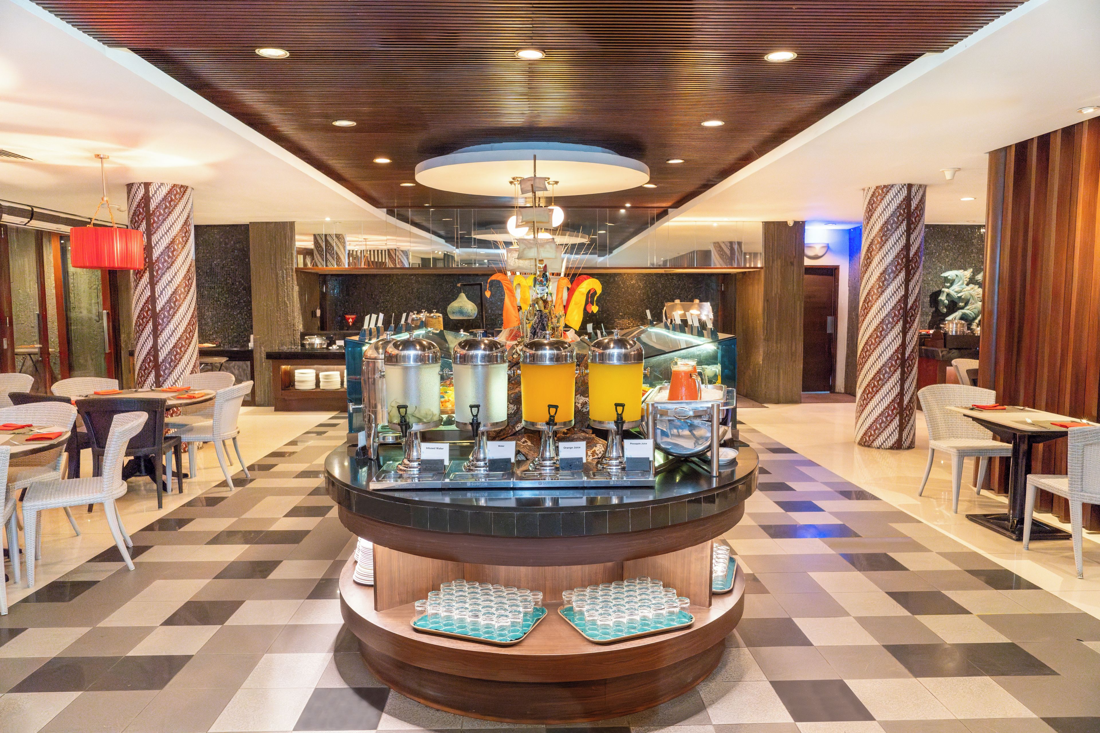 A hotel lobby with a central bar area, seating arrangements, and a check-in counter.
