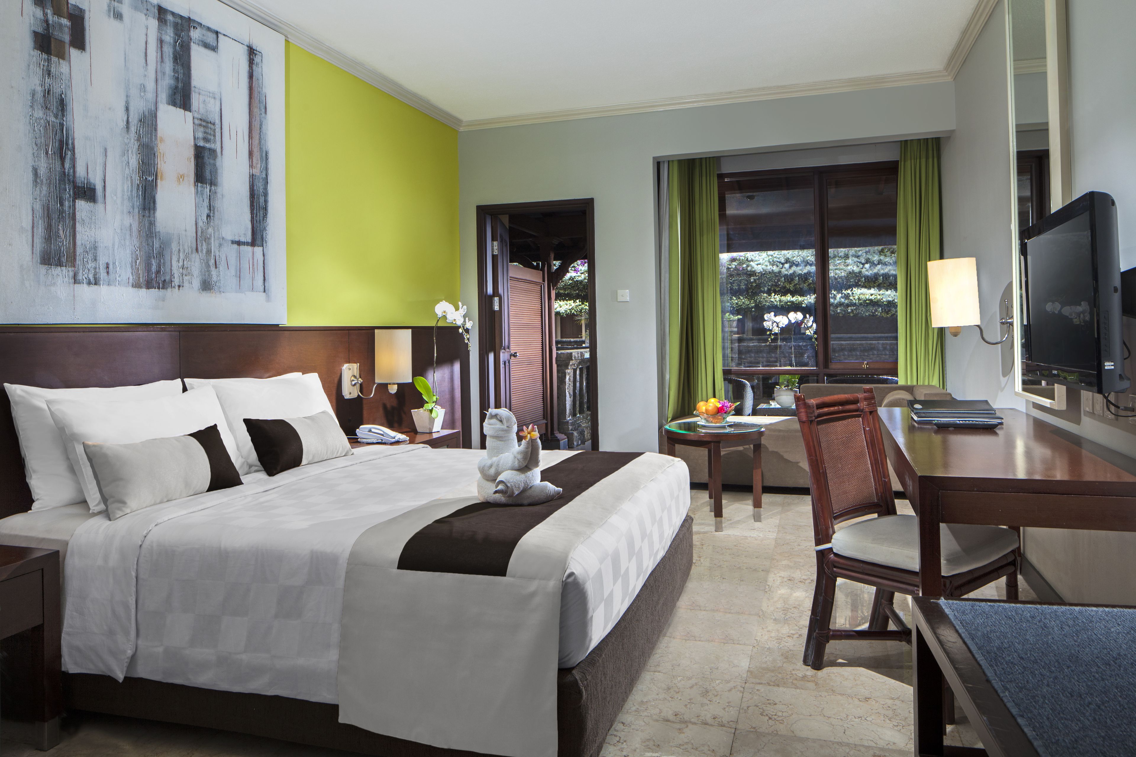Habitación de hotel con una cama grande, un escritorio, una silla, un televisor y una ventana con vistas al exterior.
