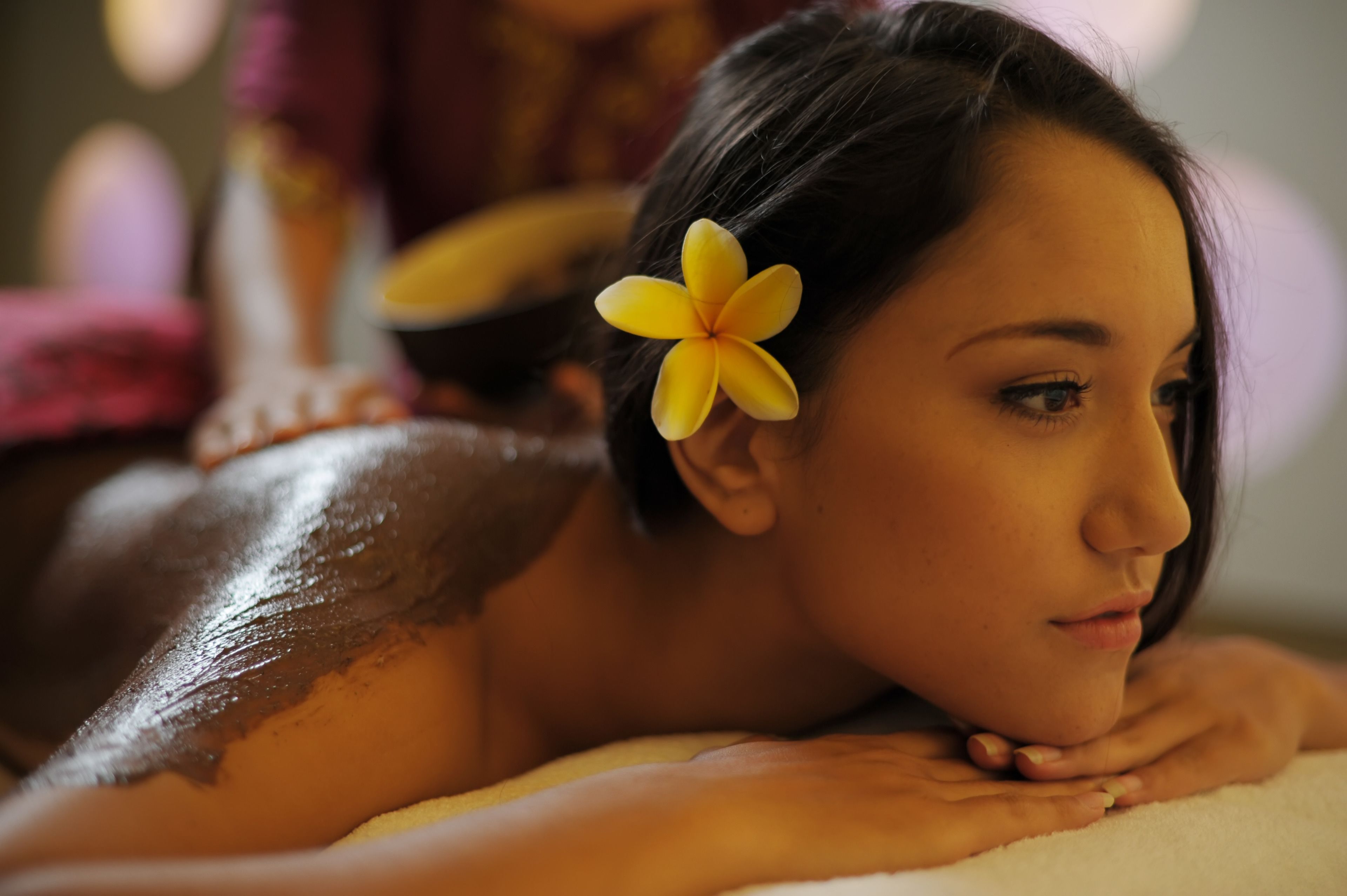 Une personne qui reçoit un massage et porte une fleur dans les cheveux.
