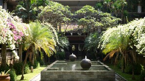 Un jardin paisible, agrémenté d’un élément aquatique central, d’une végétation luxuriante et de plantes en fleurs.