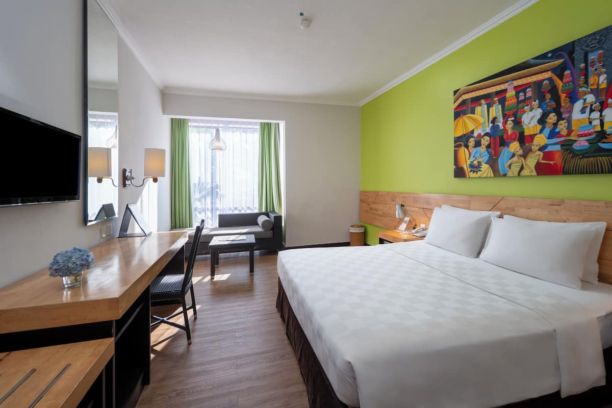 Ein Hotelzimmer mit Bett, Schreibtisch, Stuhl, Fernseher und einem Bild an der Wand.