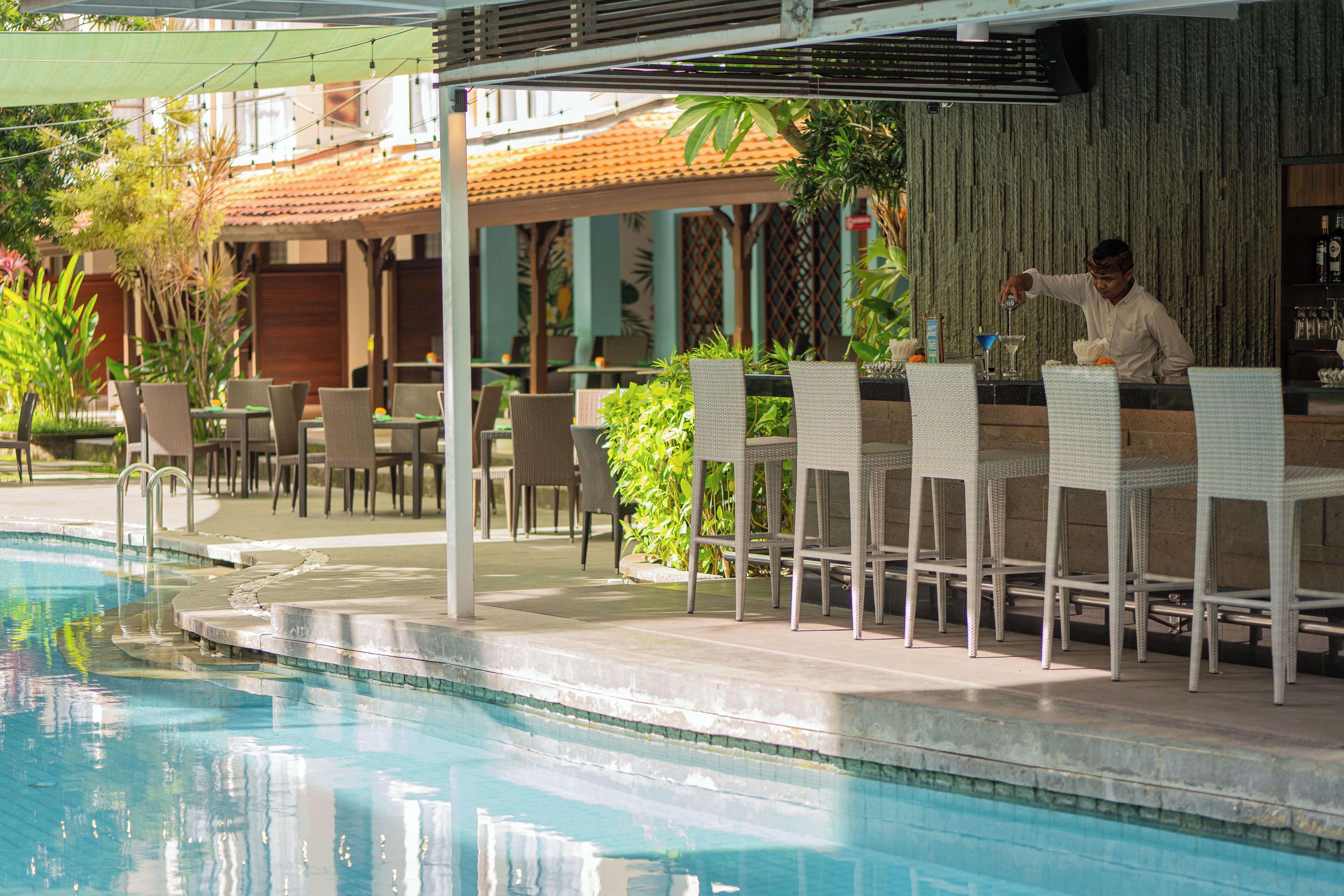 Zona junto a la piscina con bar, asientos y piscina.
