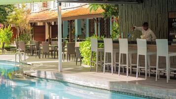 Zona junto a la piscina con bar, asientos y piscina.
