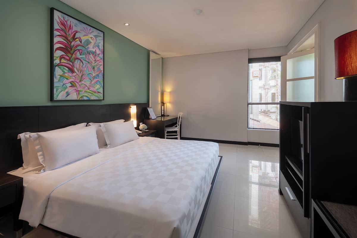 Ein Hotelzimmer mit Bett, Schreibtisch, Stuhl, Fernseher und einem großen Fenster.