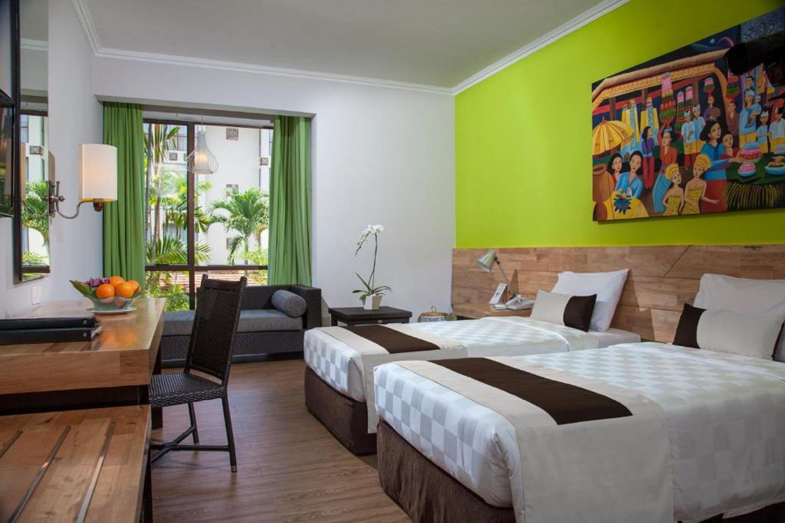A hotel room with two beds, a desk, a chair, a window with curtains, and a painting on the wall.