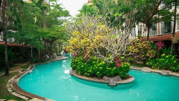 A swimming pool surrounded by lush greenery and palm trees.