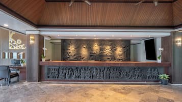 A reception area with a wooden ceiling, a marble floor, and a wall with intricate carvings.