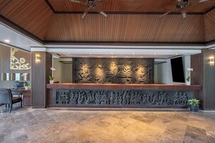A reception area with a wooden ceiling, a marble floor, and a wall with intricate carvings.