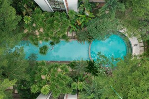 An aerial view of a swimming pool surrounded by lush greenery and a modern building structure.