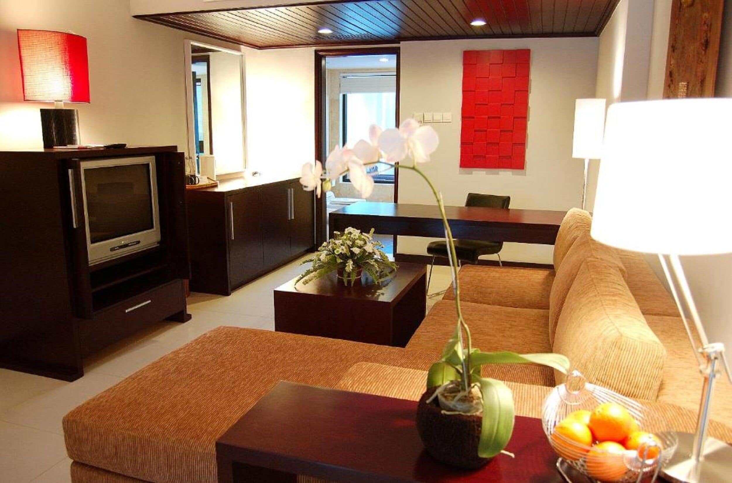 A modern living room with a television, sofa, coffee table, and decorative items.