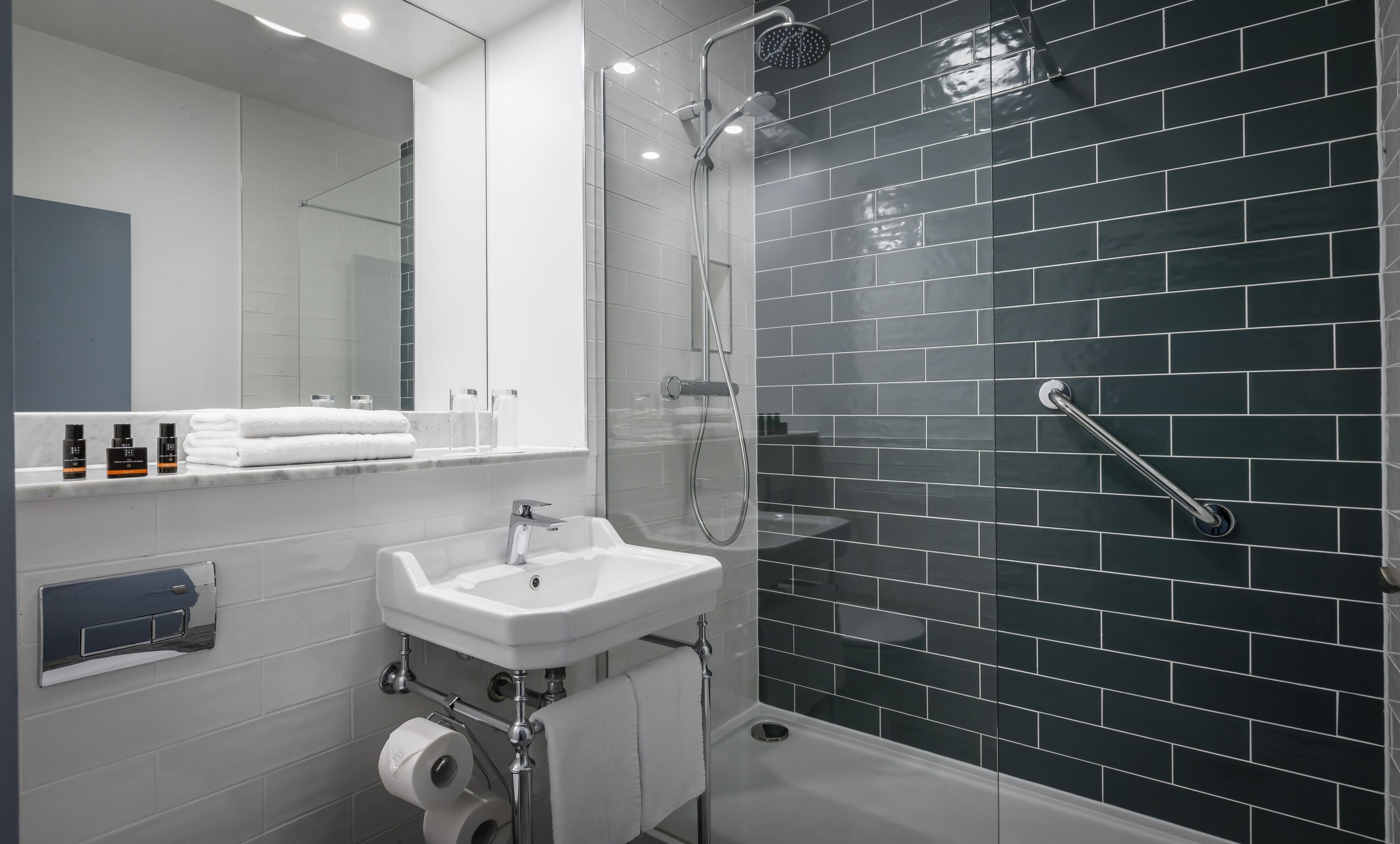 A modern bathroom with a glass-enclosed shower, a white sink, and a mirror above the sink.