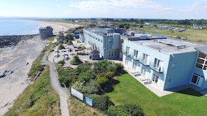 A coastal hotel with a patio area, a beach view, and a parking lot. - Shoreline Hotel (Donabate)