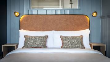 A neatly made bed with a patterned headboard and pillows, two bedside tables, and a mirror above the bed.