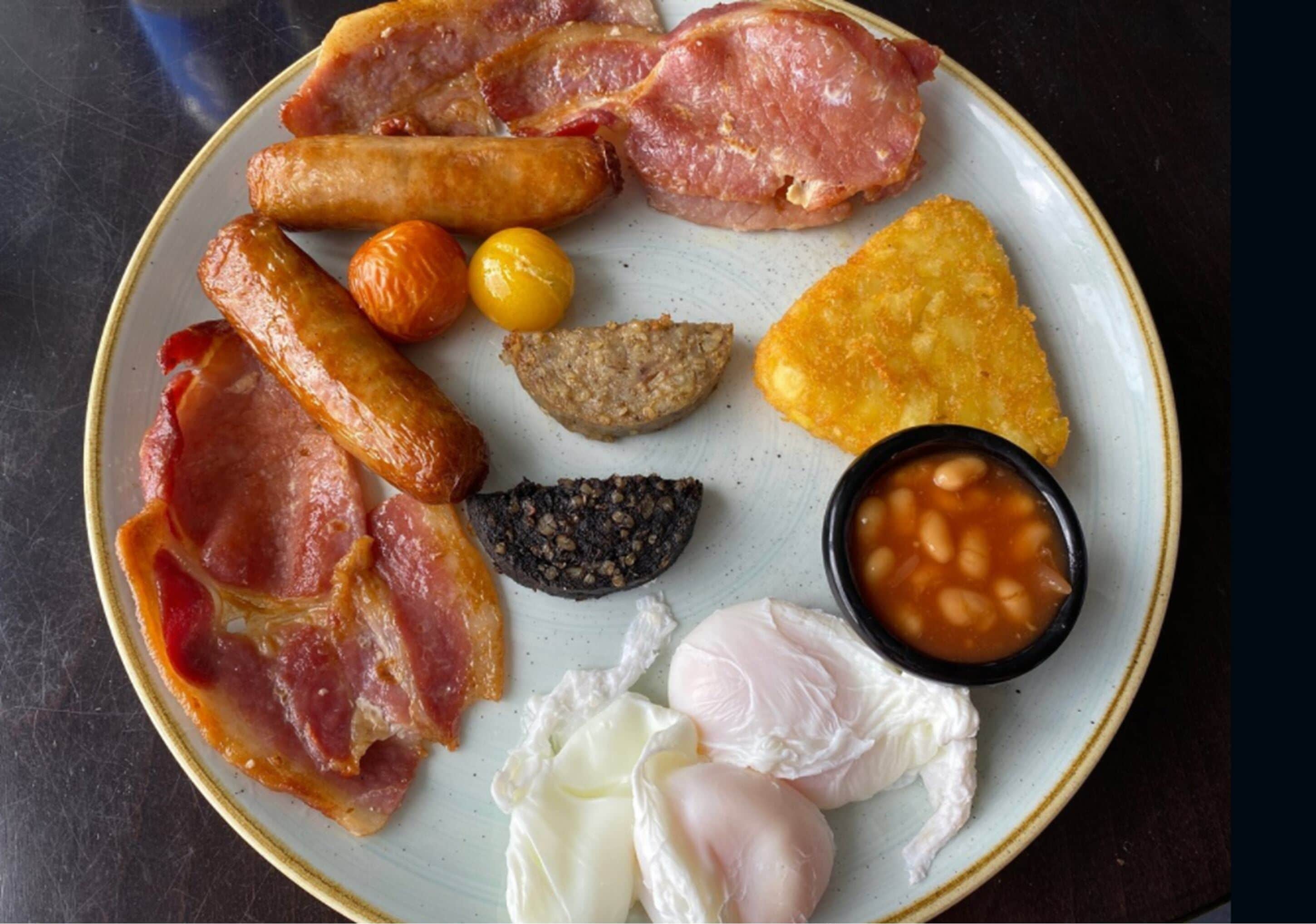 A plate with various breakfast items including bacon, sausages, eggs, and beans.